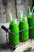 Grüne Smoothies in kleinen Glasflaschen mit einer Himbeere dekoriert