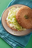 A bagel filled with cucumber, feta cheese and alfalfa sprouts