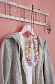 A homemade necklace of wooden beads, some painted, hanging on an old-fashioned coat rack