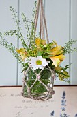 Glass vase of flowers in macrame hanger