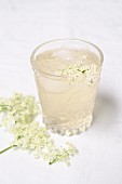 A glass of elderflower spritzer with ice cubes