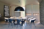 Pendant lamp with black hemispherical lampshade above dining set with designer chairs