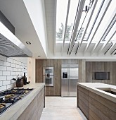 Designer kitchen with wooden board fronts under glass roof