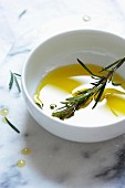 Olivenöl und Rosmarin in weißem Schälchen