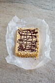 An amaranth bar with chocolate and cashew nuts on a piece of paper