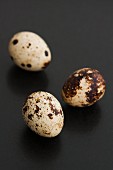 Three quail's eggs on a black surface