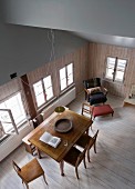 View down into renovated dining room in old wooden house with open sloping roof