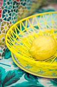 Lemon in yellow basket on colourful plate
