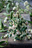 Miniature Christmas trees and mistletoe berries on wooden table