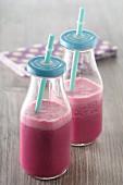 Beetroot smoothies in glass bottles with straws