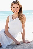 A young woman on a beach wearing a white mini dress