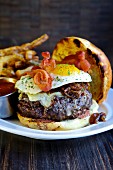 A beefburger with fried egg, onions and bacon