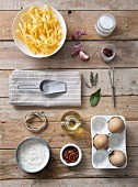 Fresh tagliatelle with ingredients on a wooden surface