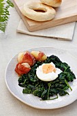 Poached egg on a bed of spinach with bacon-wrapped potatoes