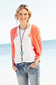 A young woman on the beach wearing a top, a cardigan and jeans