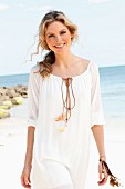 A young woman on a beach wearing a white tunic dress