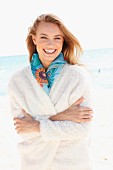 A young woman on a beach wearing a fluffy white jacket