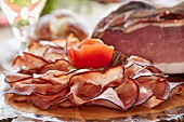 A platter of ham garnished with a tomato rose
