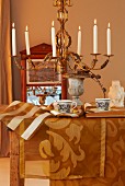 Herbstliche Tischdekoration mit goldfarbenen Tischläufern und Kronleuchter mit brennenden Kerzen
