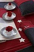 Festive table decoration in red and grey with place mats, tablecloth, napkins and cushion