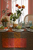 Herbstlich gedeckter Tisch dekoriert mit Rosen, Beeresträussen und Artischocken