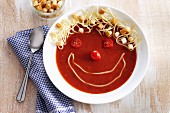 Funny tomato soup with cheese strings and croutons
