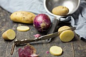 Rote Zwiebeln und Kartoffeln auf rustikalem Tisch