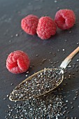Chia seeds and raspberries on a grey surface