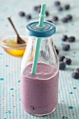 A blueberry smoothie in a glass bottle