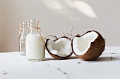 An open coconut and a bottle of coconut milk