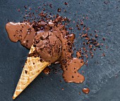 A fallen ice cream cone with melting chocolate ice cream