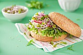 A bagel with cucumber, avocado, radish sprouts and radishes