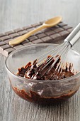 Melted chocolate with a whisk in a glass bowl