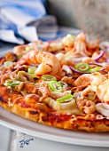 Pizza with seafood, olives and spring onions (detail)