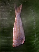 A fish fillet being steamed on a banana leaf