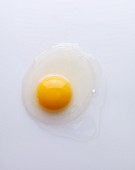 A freshly cracked egg on a white surface