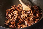 In Olivenöl gebratene braune Champignons mit gehacktem Knoblauch im Wok