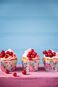 Cupcakes mit rosa Buttercreme und roten Johannisbeeren