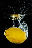 A lemon falling into water with a splash