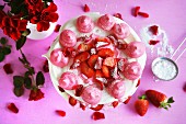 Meringue cake with cream, strawberries and rose petals (seen from above) decorated with roses and strawberries