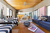 Offener Loungebereich mit Blick auf Essbereich und Küchenzeile in Architektenhaus mit Betonwänden, Holzdecke und modernen Kunstbildern