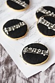 Round cookies with black icing on a piece of sheet music