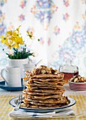 A stack of pancakes with banana and pecan nuts