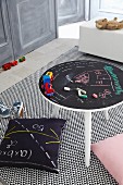 Mit Tafelfarbe bemalter Spieltisch auf grafisch gemustertem Teppich
