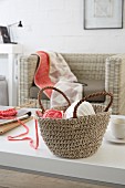 Ball of knitting yarn in rustic crocheted basket on white table