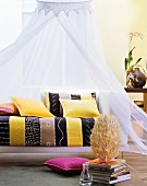 Colourful cushions on ethnic-style couch below canopy