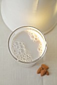 Almond milk in a glass in front of a white jug