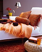 Orange cushions and knitting on white chaise longue
