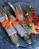 Cutlery wrapped in felt and raffia on glass plate