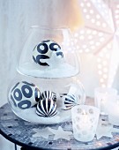 Black and white patterned baubles in glass vessels on mosaic-tiled table